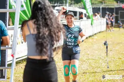 Corredora con la camiseta PZ Backyard celebra justo después de cruzar la línea de meta